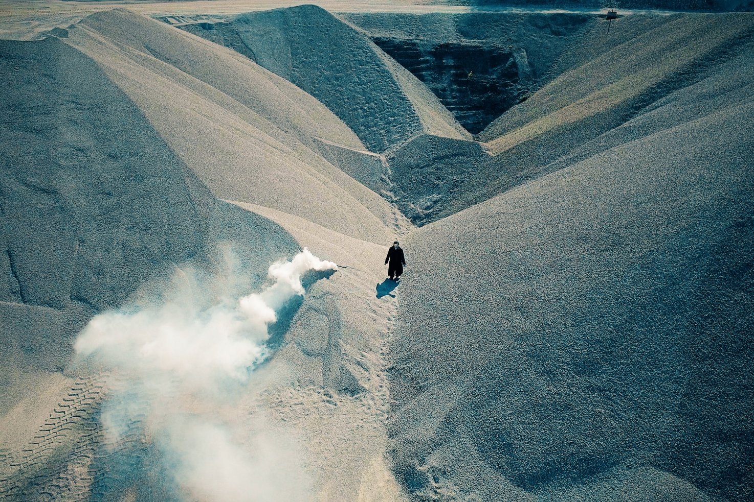 Eine Person steht in einer Sandgrube. Links von ihr brennt ein Bengalofeuer.